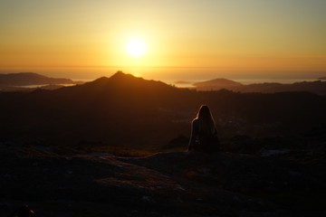 Young woman contemplating the sunset from Mount Galiñeiro in Vigo, Galicia, Spain