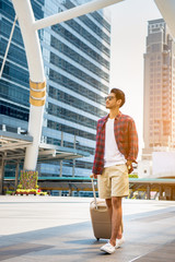 Portrait happy tourists taking walk and dragging luggage bags in town on summer day
