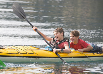 Obraz premium Brothers and friends enjoying their summer vacation in a kayak