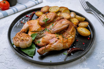 fried chicken tobacco with mini potatoes on black plate