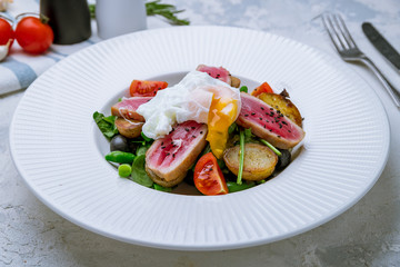 Nicoise with tuna and poached egg on white plate