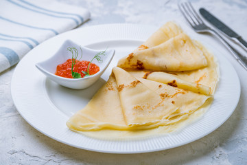 pancakes with red caviar on a white plate