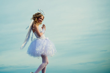 Fototapeta na wymiar Love concept. Happy teenage angel girl pray. Portrait of little curly blond Angel girl. Angel wings baby pray. Pretty white little girl as the cupid congratulating on St Valentines day. Pray.