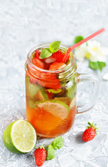 Mojito lemonade with strawberries on a dark background in a trendy mug pot.