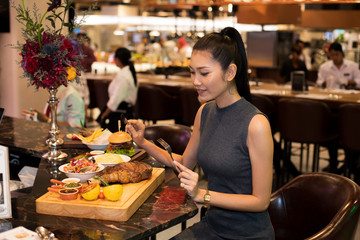 Fototapeta na wymiar Working Asian Woman Black hair having Lunch big piece Steak grill Dinner of Western food in fusion restaurant cafe and eat alone. Concept enjoy eating myself for good food life