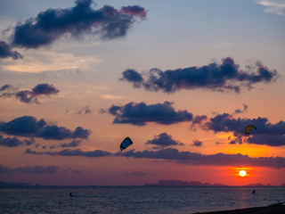 Fototapeta na wymiar Silhouette people kitesurfing sunset clouds. Koh Phangan. Thailand