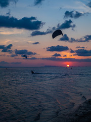 Silhouette people kitesurfing sunset clouds. Koh Phangan. Thailand