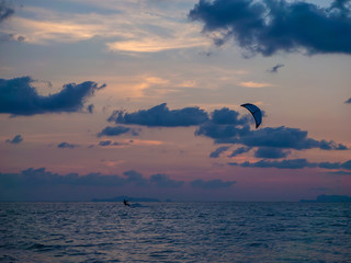 Fototapeta na wymiar Silhouette people kitesurfing sunset clouds. Koh Phangan. Thailand