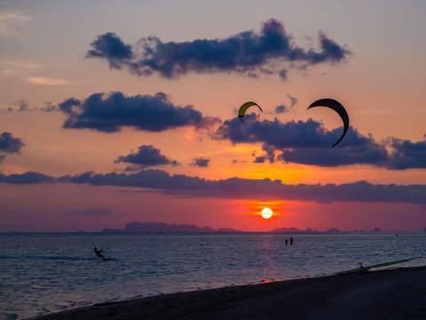 Silhouette people kitesurfing sunset clouds. Koh Phangan. Thailand