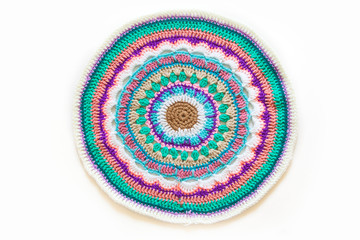 Round mandala crocheted from colored yarn. White background.