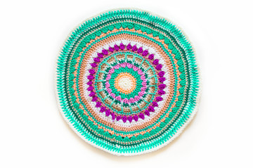 Round mandala crocheted from colored yarn. White background.