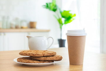 Cup of coffee take-away and sugar cookies in the kitchen with sunlight.
