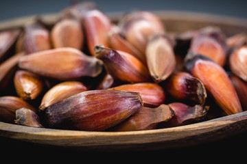 Brazilian pine in brown wooden rustic bowl. Typical araucaria tree seed used as a condiment in Brazilian cuisine in winter.