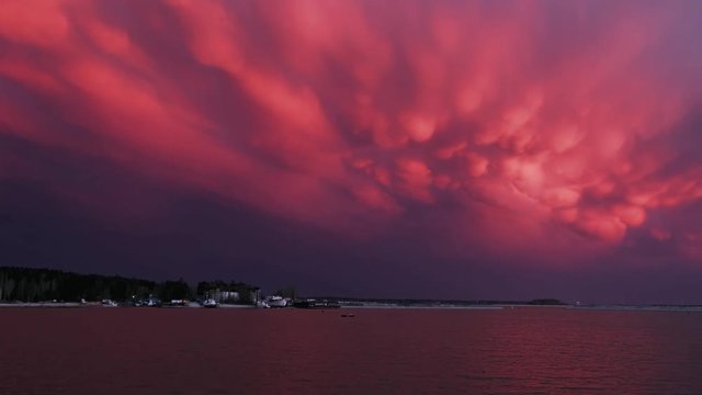 Time lapse video of amazing dramatic sunset with cumulus mammatus clouds over water of Ob Sea
