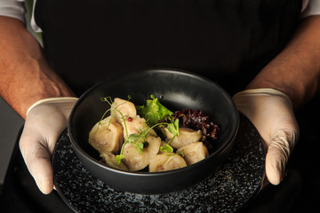 waiter hands hold boiled meat dumplings with salad in bowl