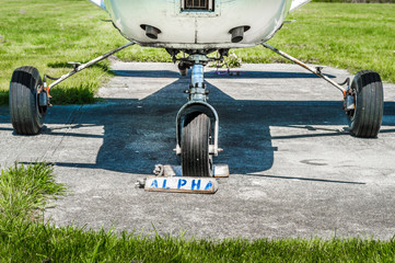 Small single engine airplane wheels and landing gear on parking pad with wheel chocks.