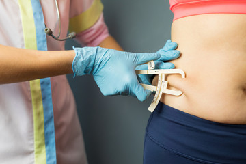 Doctor taking patient's body fat measurements with fat caliper
