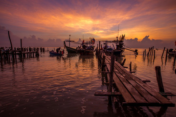 Fototapeta na wymiar The background of the morning sunrise scenery by the sea, the fishing boats parked in the blurred beauty of the sea breeze that passes through, is the beauty of nature during traveling. 