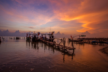 The blurred background of the morning twilight by the sea, changing the color of the beautiful sky, there is a fishing boat docked waiting to go out to find fish again.