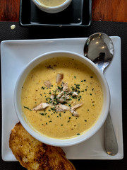 Corn soup in the white cup with garlic bread on the wooden table