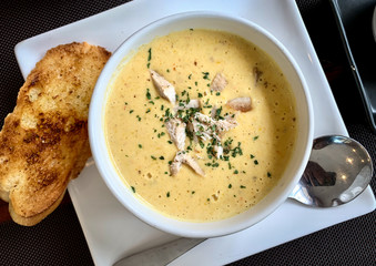 Corn soup in the white cup with garlic bread on the wooden table