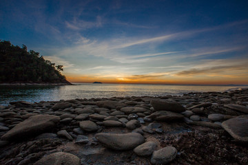 Obraz premium Natural close-up wallpaper of a seaside atmosphere, with a secret light, a beautiful twilight sky, with rocks of varying sizes, with forests, cool air of the wind blowing all the time. 