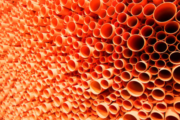 orange PVC pipes stacked in construction site