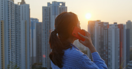 Woman talk to cellphone in the background of the city under sunset time