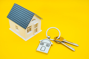 key chain with house symbol and keys on yellow background,Real estate concept