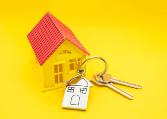key chain with house symbol and keys on yellow background,Real estate concept