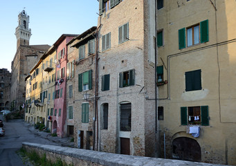 Fototapeta premium typical street view in the historic center of Siena medieval town with Torre del Mangia in the background 