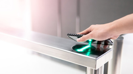 Male hand using smartphone to open automatic gate machine in office building