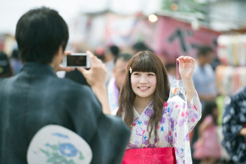 お祭りで金魚の入った袋を持ち写真を撮るカップル