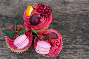 appetizing cupcakes decorated with macarons grape and pomegranate