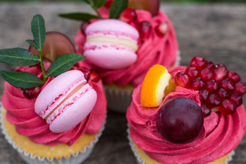 appetizing cupcakes decorated with macarons grape and pomegranate