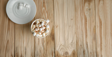 Hot morning coffee with marshmallow and cinnamon on a wooden sta