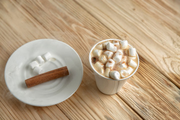 Hot morning coffee with marshmallow and cinnamon on a wooden sta