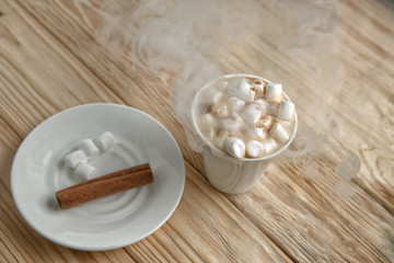 Hot morning coffee with marshmallow and cinnamon on a wooden sta