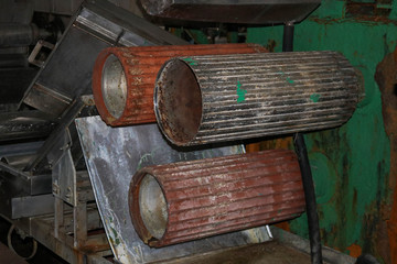 Large metal rollers rolls with teeth of the gears of the production line, a conveyor belt in the...