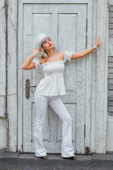 Sexy modern bride in white cylinder hat standing next to old vintage door.