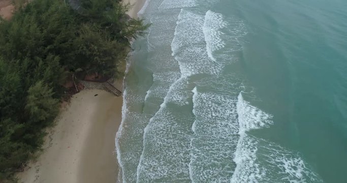 Drone flying over the sea panning up to reveal coast line and waves rolling in at Mae Pim beach Rayong Thailand