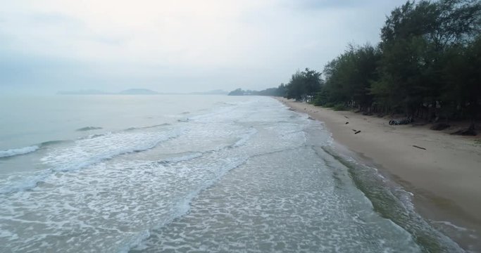 Drone flying low over the sea during the morning mist watching the waves roll in at Mae Pim beach Rayong Thailand