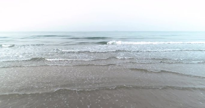 Drone flying above the sea and waves rolling into the Mae Pim beach Rayong Thailand