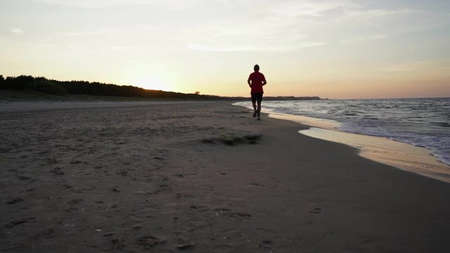 Slow motion of a man running on the beach at sunset in Swinoujscie, Poland