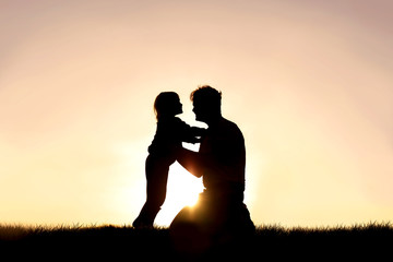 Silhouette of Happy Father and his Little Child Smiling and Playing at Sunset