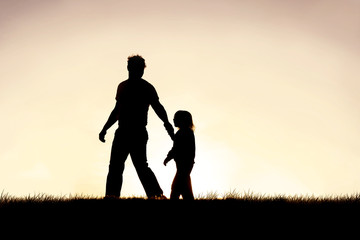 Fototapeta na wymiar Silhouette of Christian Father Guiding his Young Child by the Hand