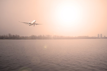 Fototapeta na wymiar Airliner over the river and the dark forest. The evening sunset.