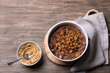 Delicious oatmeal in a white bowl, dates fruits and cocoa. healthy breakfast on a wooden background