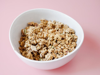 Cereal corn flake whole grains in white bowl on pink background.