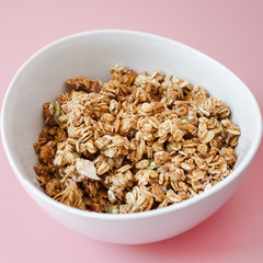 Cereal corn flake whole grains in white bowl on pink background.